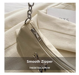 Detailed close-up of cream-white bag featuring silver zipper and metal bow charm