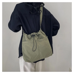 Detail of army green nylon bucket bag featuring drawstring closure and front pockets