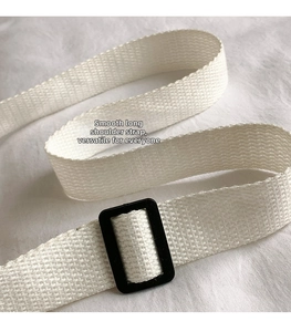 Detail of adjustable white woven shoulder strap with black buckle on corduroy bag