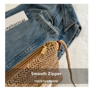 Close-up of golden metal zipper on woven straw bag with rope strap and denim background