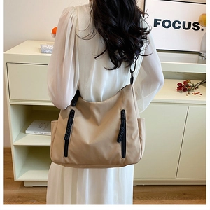 Detail of khaki nylon tote bag with dual decorative black zippers for student commuting