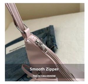 Macro detail of smooth silver metal zipper and stitching on pink leather shoulder bag