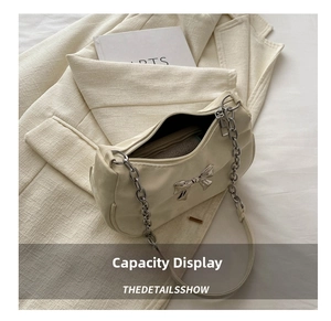 Detailed interior capacity of cream shoulder bag with silver bow and chain strap