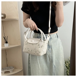 Detail of hand-woven straw bag with floral embroidery and vegan leather handles