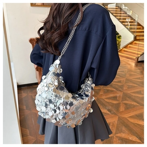 Detail of silver sequin crescent shoulder bag with metallic chain on street style outfit