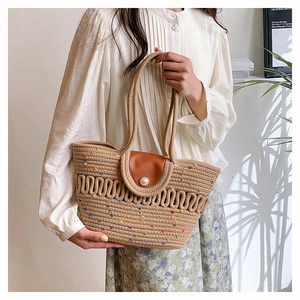 Close-up of hand-woven straw bag featuring leather flap and elegant pearl closure detail
