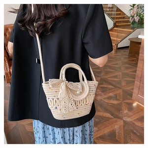 Detail of hand-woven straw bag featuring a lace bow, pearl buckle and matching strap