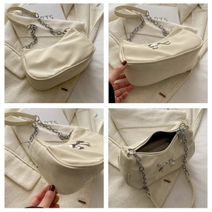 Detailed view of cream leather underarm bag with silver bow accent and chunky chain strap