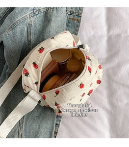 Detail view of small corduroy crossbody bag with strawberry print and zipper closure