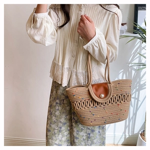 Detailed straw tote bag with colorful specks, leather flap, and large pearl buckle closure