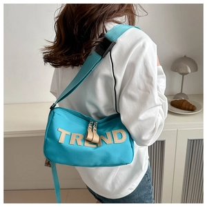 Detail of blue oxford fabric shoulder bag with TREND patch and adjustable strap