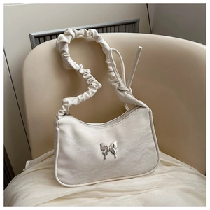 Detail of white pleated crescent bag featuring silver butterfly and scrunched shoulder strap