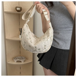 Detailed embroidery of green leaves and red flowers on a cream crocheted shoulder bag