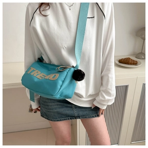 Detail of lake blue crossbody bag with TREND embroidery and black plush ball charm