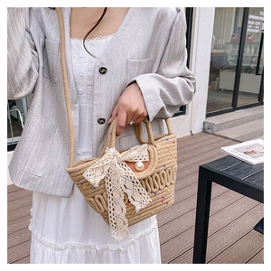 Detail of woven straw tote bag with delicate lace bow and white pearl button decoration