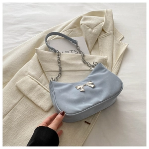 Detail of light blue hobo bag featuring silver metal bow and chain shoulder strap