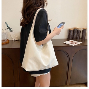 Close-up of a minimalist beige PU leather shoulder bag worn over a woman's shoulder