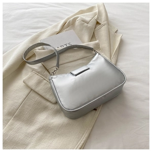 Detail showing the metallic silver bow handbag placed on a beige blazer fabric texture