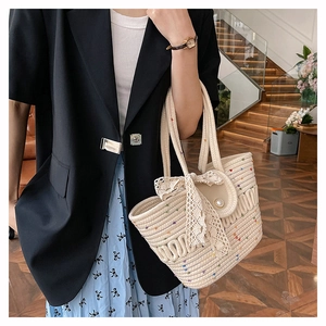 Detail of woven straw bucket bag with lace bow, pearl buckle and colorful polka dots