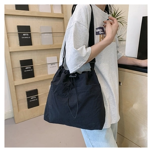 Detailed view of black nylon drawstring tote bag with adjustable shoulder strap