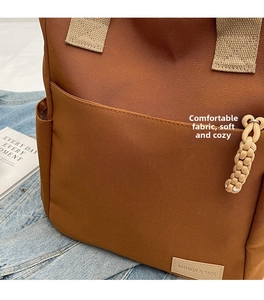 Dettaglio borsa a tracolla in tela marrone con cerniera e decoro in corda intrecciata
