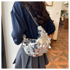 Detailed view of silver sequin shoulder bag with sleek metal chain strap on a model