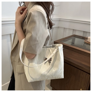 Détail du sac à bandoulière plissé blanc avec pendentif papillon argenté et chaîne métal