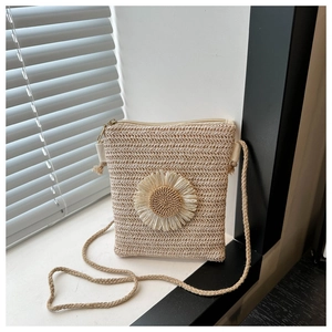 Macro detail of hand-woven straw crossbody bag with decorative sunflower ornament