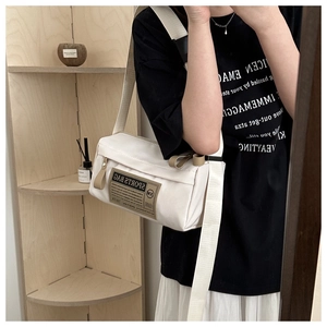 Detail of off-white crossbody bag featuring utility sports tag and wide strap