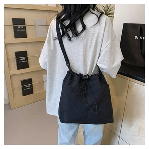 Detail showing black drawstring canvas bucket bag with wide strap and side pocket