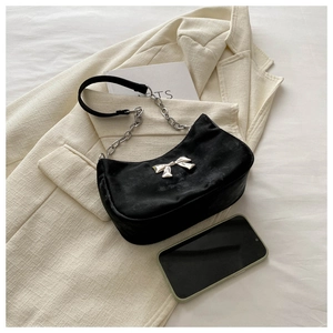 Detail of black velvet shoulder bag with silver bow buckle and chunky metal chain strap