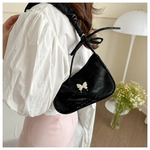 Détail du sac croissant en velours noir avec boucle papillon et bandoulière froncée