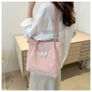Detail of light pink butterfly tote bag showing textured material and metallic pendant