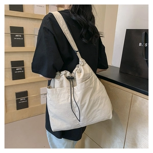 Macro shot of large beige nylon drawstring tote bag featuring two front open utility pockets