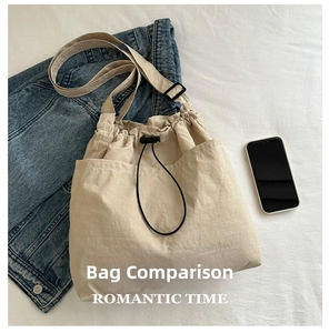 Detail of the beige drawstring tote bag showing the size compared to a smartphone