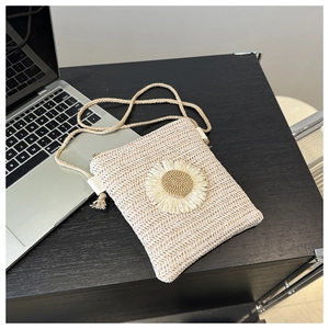 Detail showing handwoven straw texture and white daisy flower appliqué on the small bag