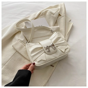 Detail of creamy white handbag showing ruched bow design and silver metal ornament