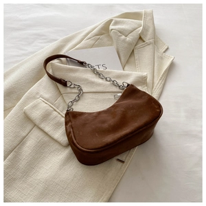 Detailed close-up of dark brown suede half-moon baguette bag with silver chain strap