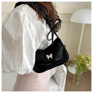 Detail of black shoulder bag featuring white butterfly decor and textured velvet finish