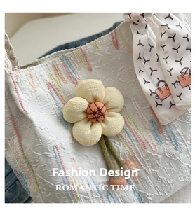 Detail of white embossed tote bag with floral pendant and colorful wave texture