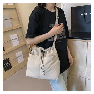 Detail of beige drawstring crossbody bag with multi-pocket design and adjustable strap