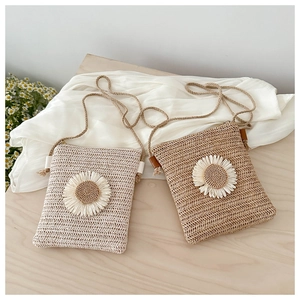 Macro view of hand-woven straw crossbody bag with white daisy flower detail