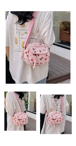 Detail view of pink corduroy crossbody bag featuring cute strawberry print and front pocket