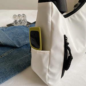 Minimalist white nylon tote bag with wide black strap and side pocket for sunglasses