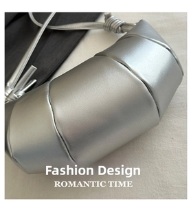 Close-up of woven silver leather croissant bag featuring a distinctive knotted shoulder strap