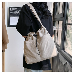 Detail of beige nylon crossbody bag featuring drawstring closure and adjustable wide strap