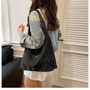 Close-up of black pleated leather tote bag with wide strap for casual daily use