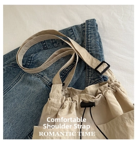 Detail of beige drawstring bucket bag featuring a wide comfortable shoulder strap