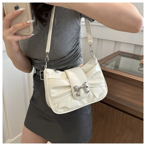 Detail of white bow shoulder bag with silver metal clasp and pleated leather texture