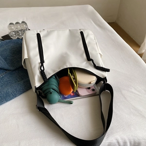 White minimalist tote bag showing large capacity with daily items and black strap
